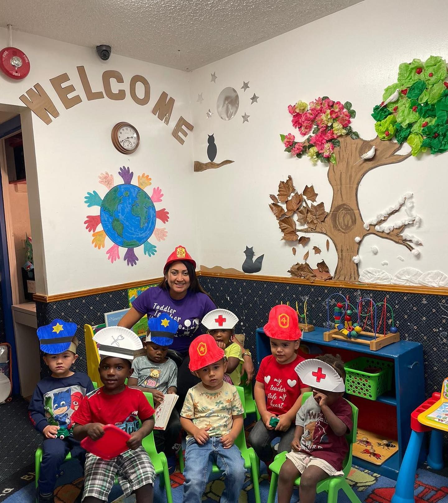 A group of children are sitting in front of a wall that says welcome