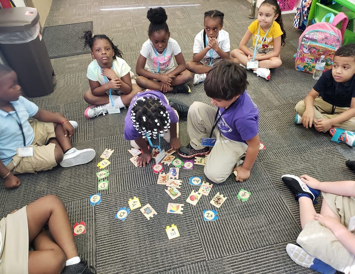 A group of children are sitting on the floor in a circle playing cards.