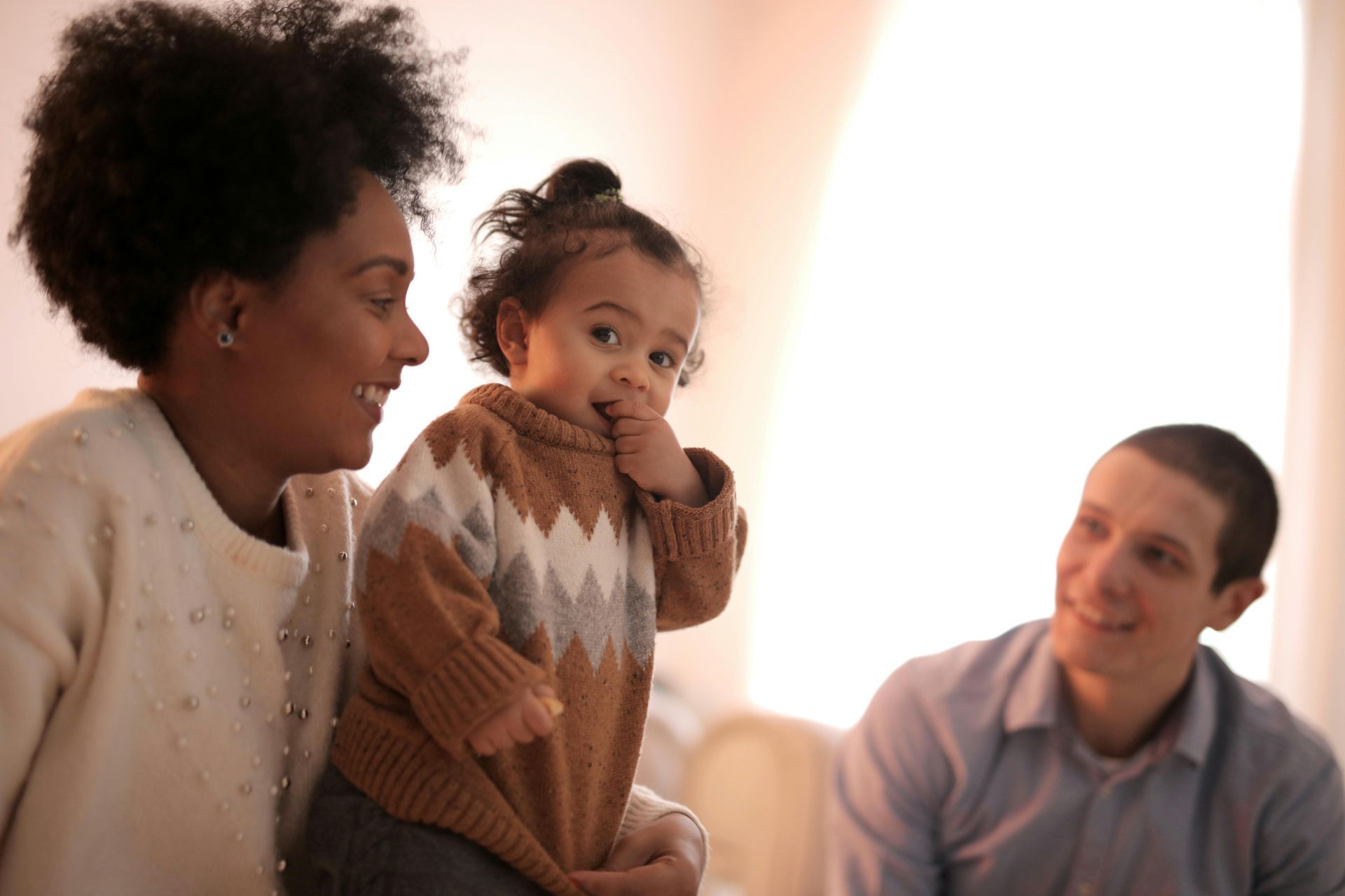 A woman is holding a baby while a man looks on.