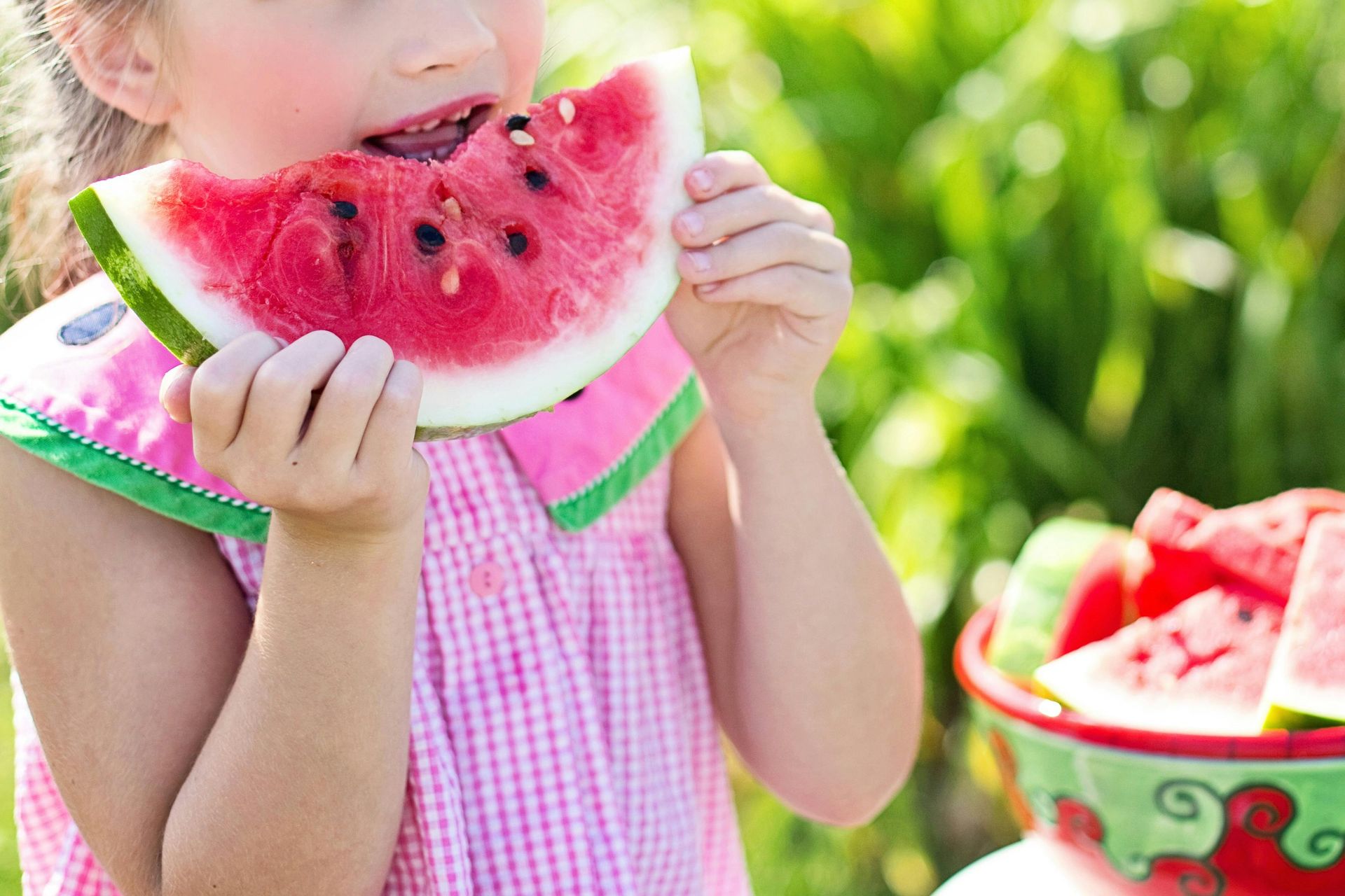A little girl is eating a slice of watermelon.