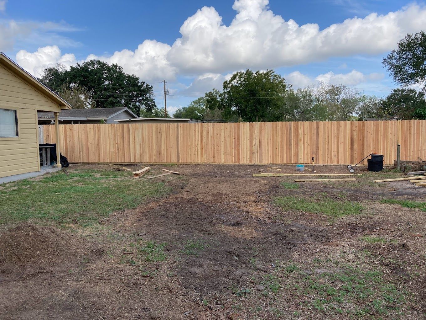 A wooden fence is in the backyard of a house.