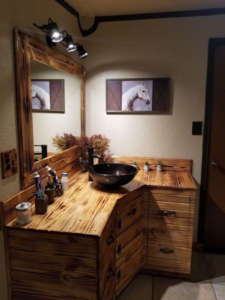 A bathroom with a wooden vanity , sink and mirror.