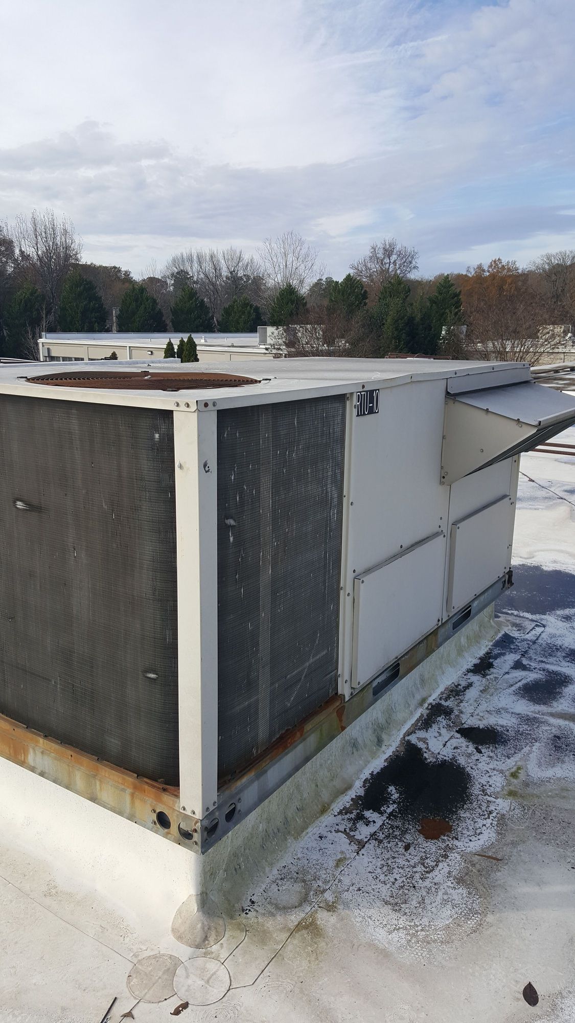 An air conditioner is sitting on top of a snow covered roof.