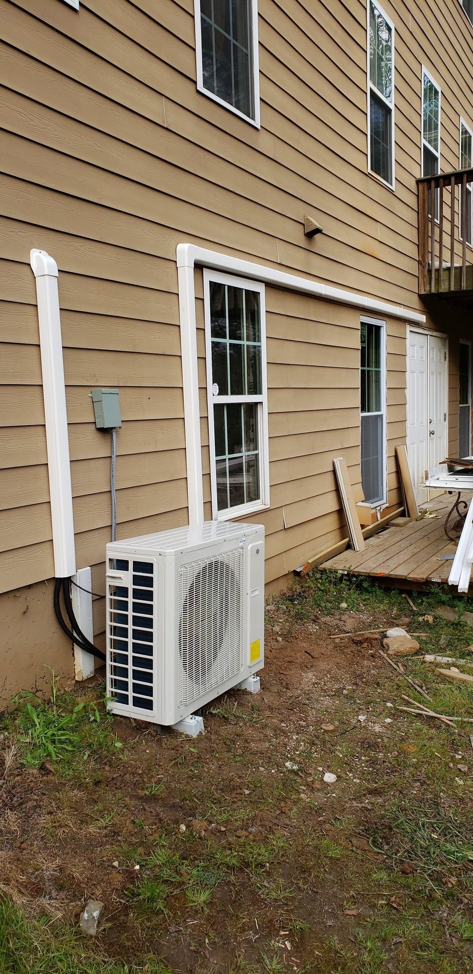 A white air conditioner is sitting on the side of a house.