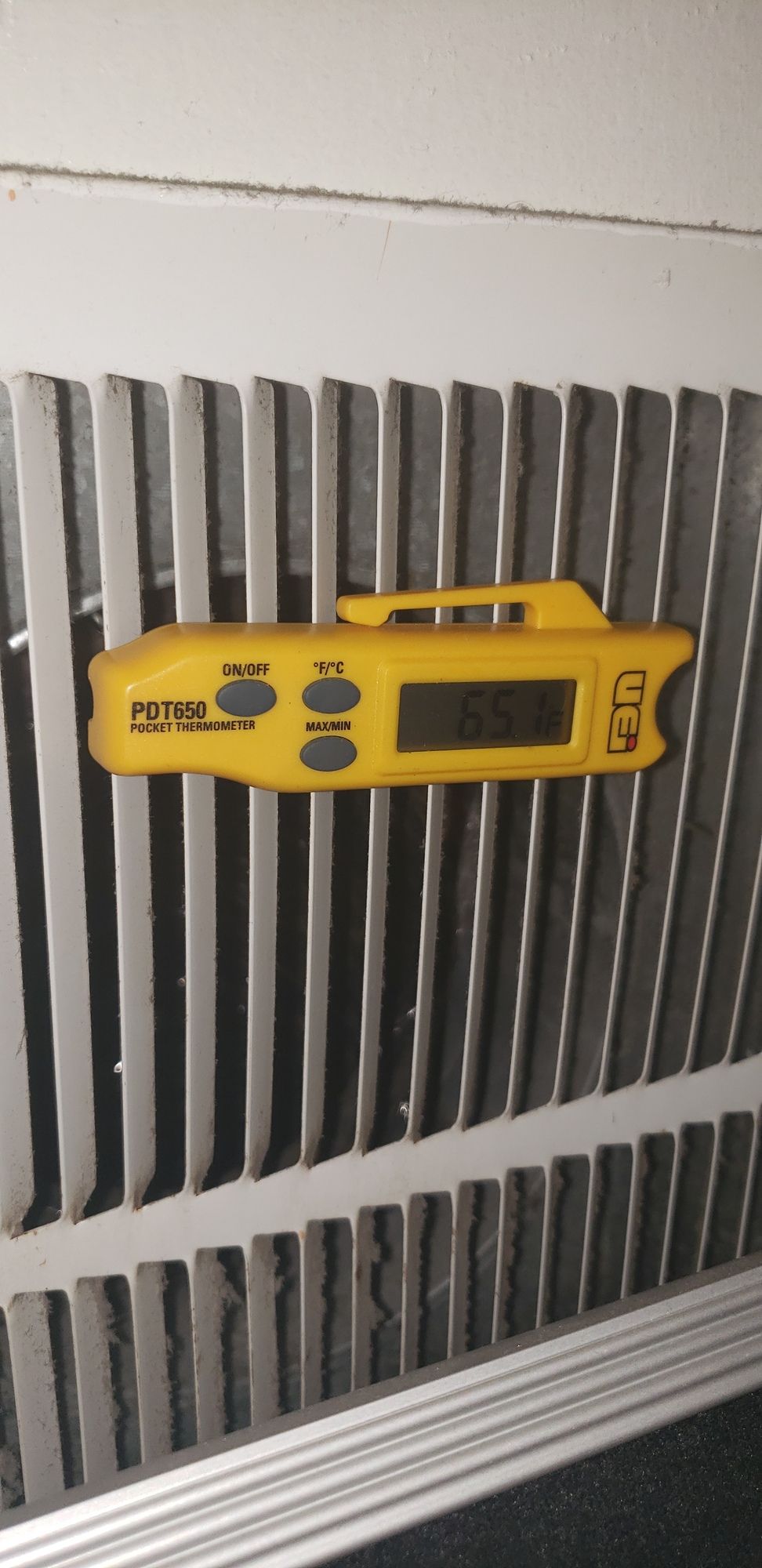 A yellow thermometer is sitting on top of a radiator.