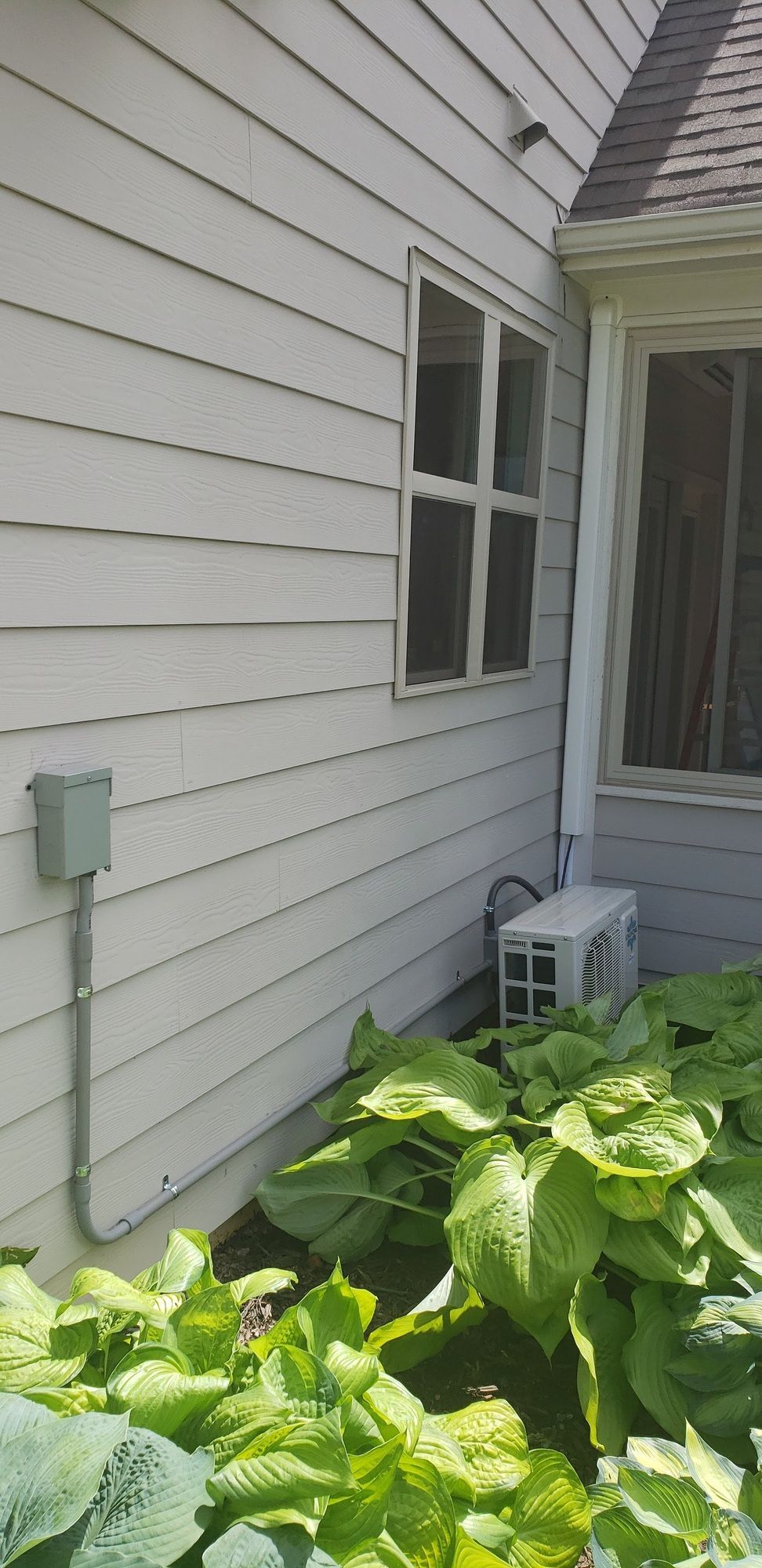 A white house with a window and a fan on the side of it.