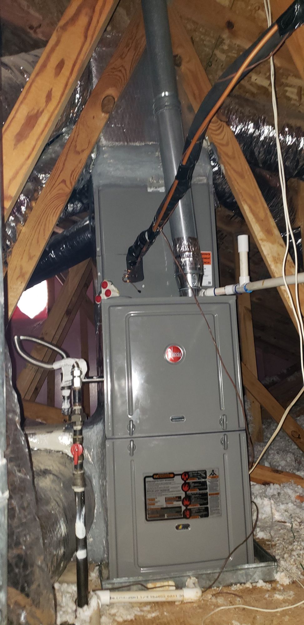 A large air conditioner is sitting in the attic of a house.