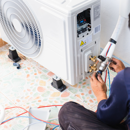 A man is working on an air conditioner on the floor.