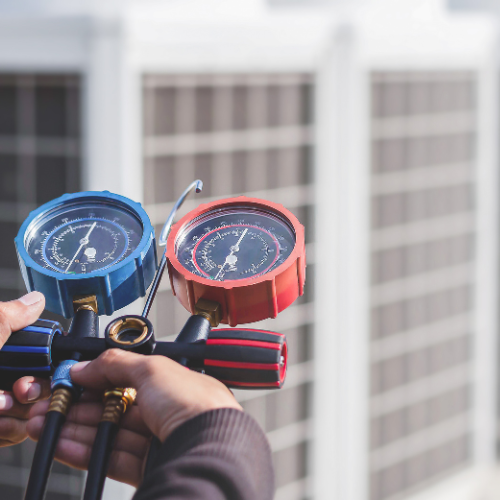 A person is holding a pressure gauge in front of a building.