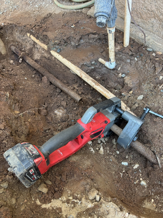 Plumber in red overalls, installing or repairing copper pipes indoors.