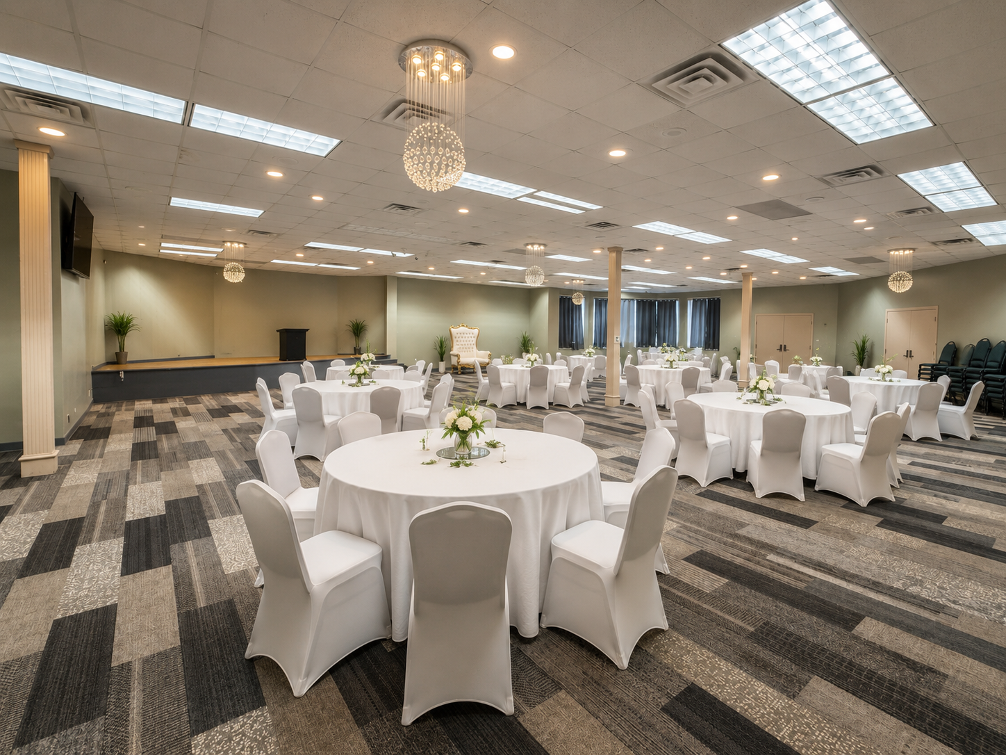 Elegant banquet hall with round white-clothed tables and chairs under bright ceiling lights