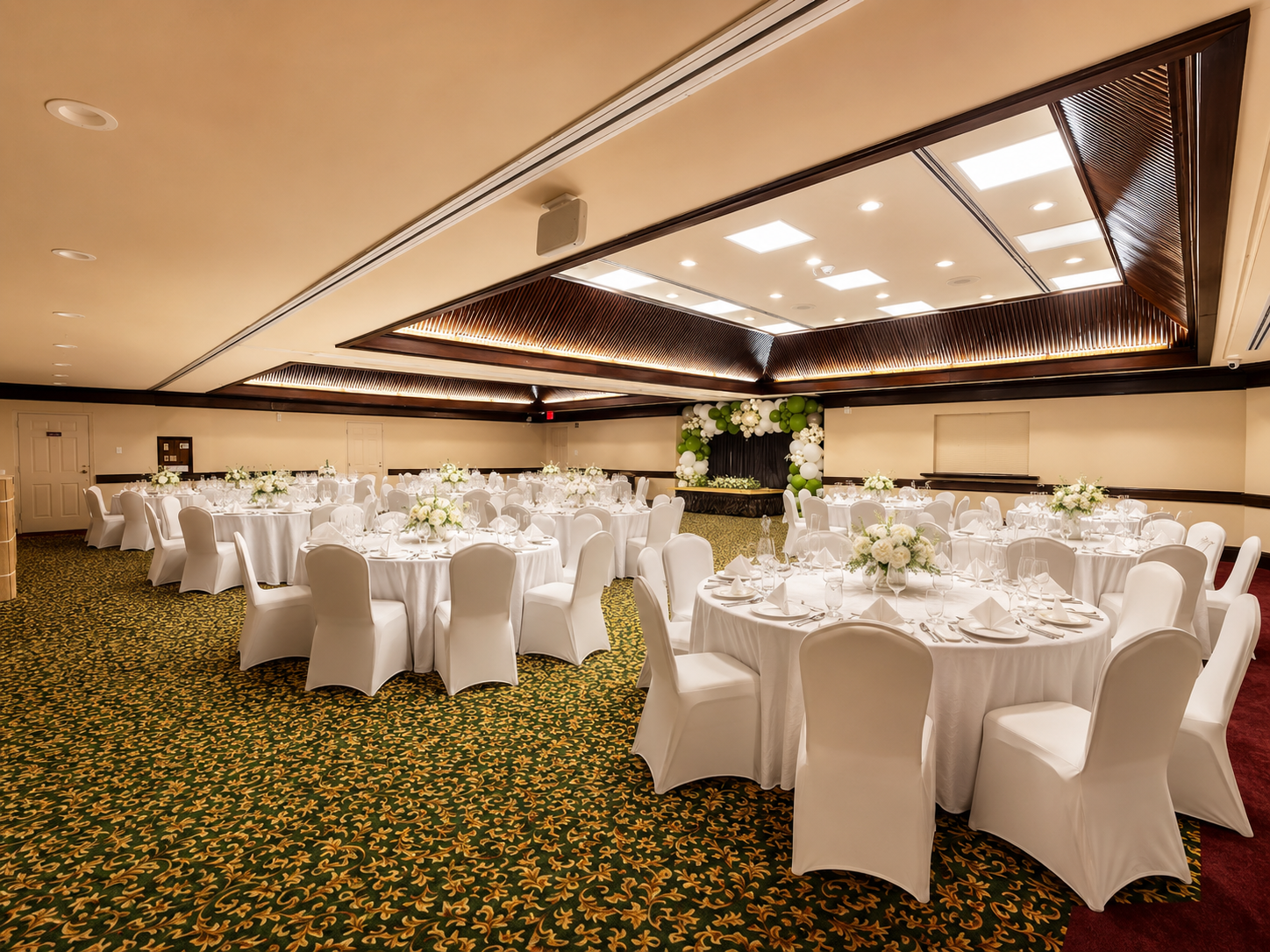 Banquet hall with round, white-tablecloth tables and chairs arranged for an event