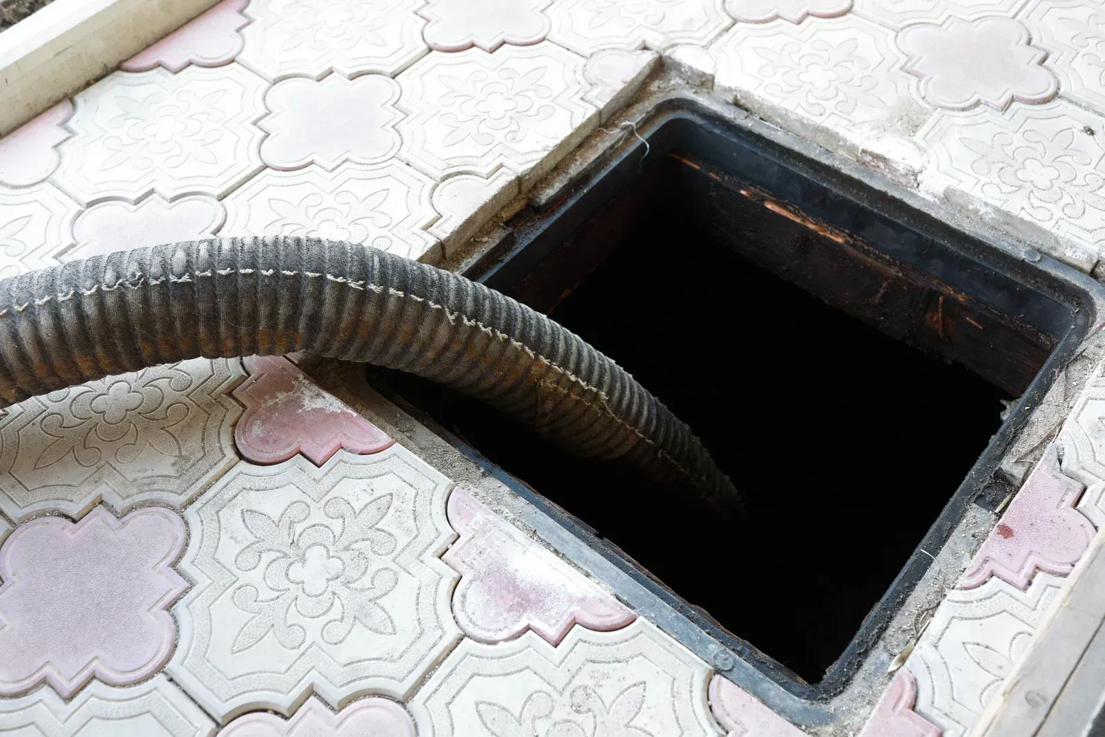 A manhole cover with a hose coming out of it.