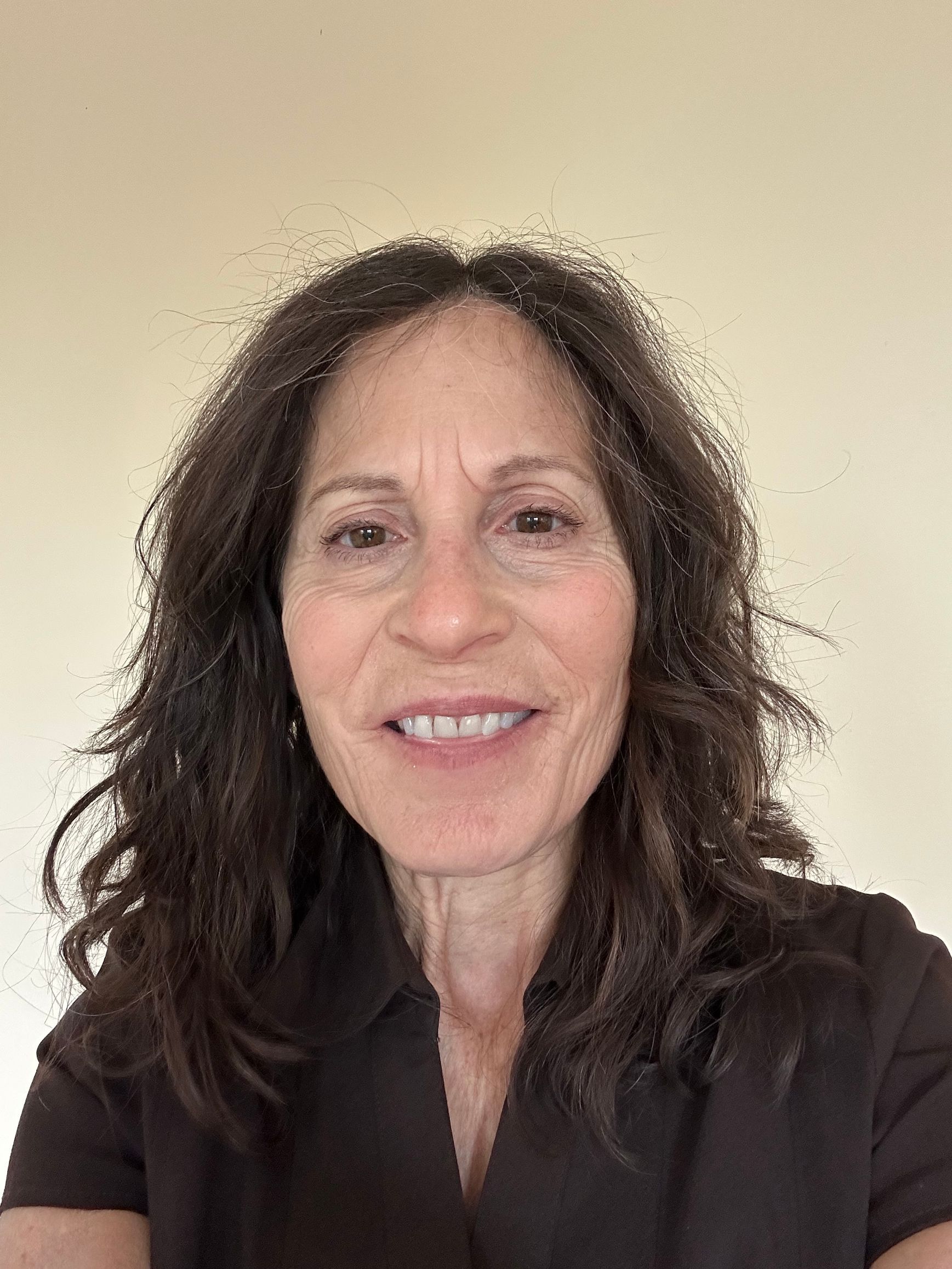 A woman wearing glasses and a floral shirt is smiling for the camera.