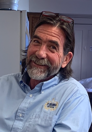 A woman wearing glasses and a floral shirt is smiling for the camera.