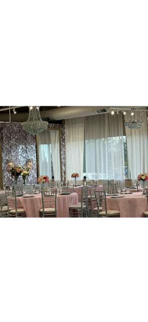 Reception hall with round tables covered in pink tablecloths and floral centerpieces.