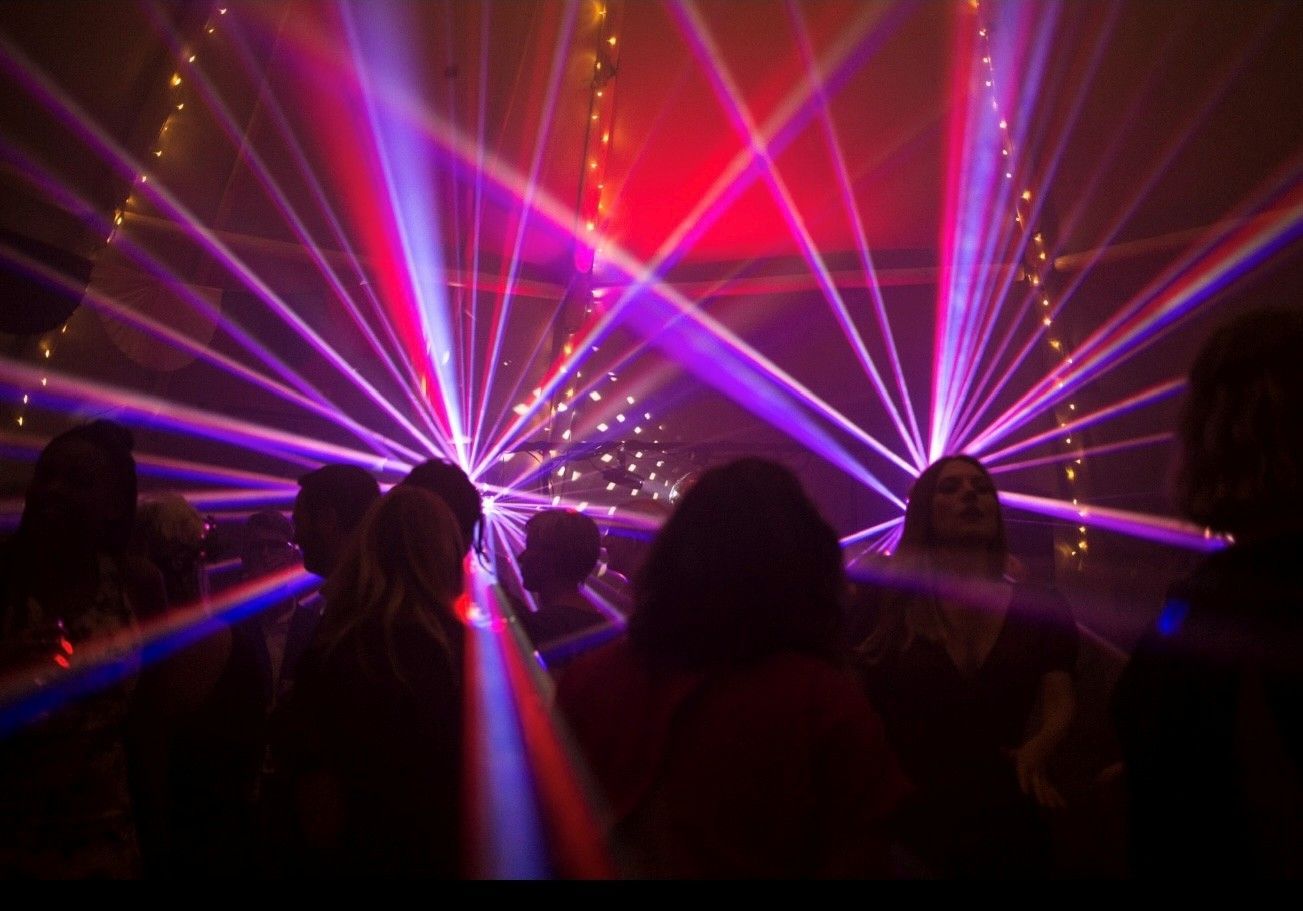 Round tables with white linens, floral centerpieces, set for a formal event. Pink flowers decorate the floor. Round tables with white linens, floral centerpieces, set for a formal event. Pink flowers decorate the floor.