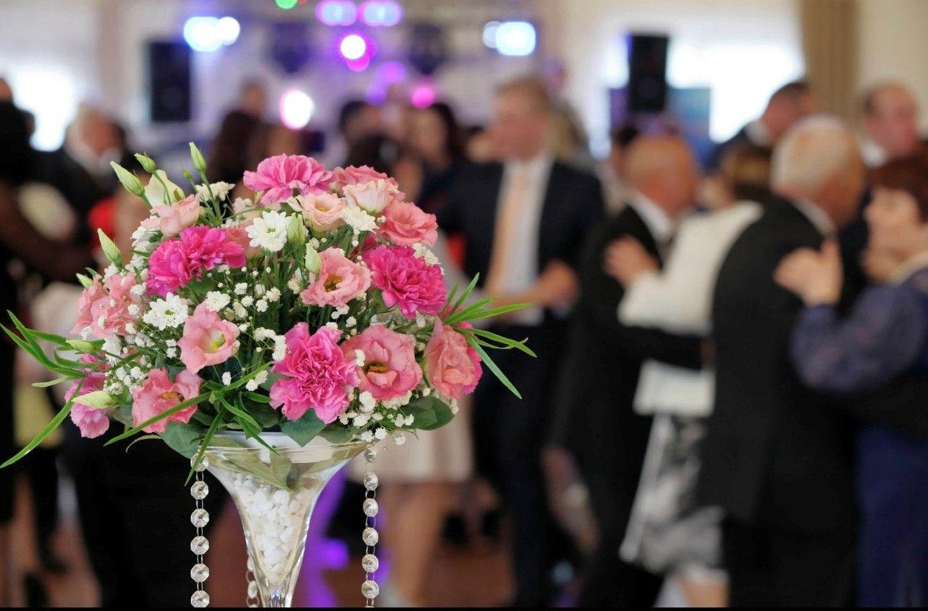 Elegant event hall with round tables, floral centerpieces, and dancers. Elegant event hall with round tables, floral centerpieces, and dancers.