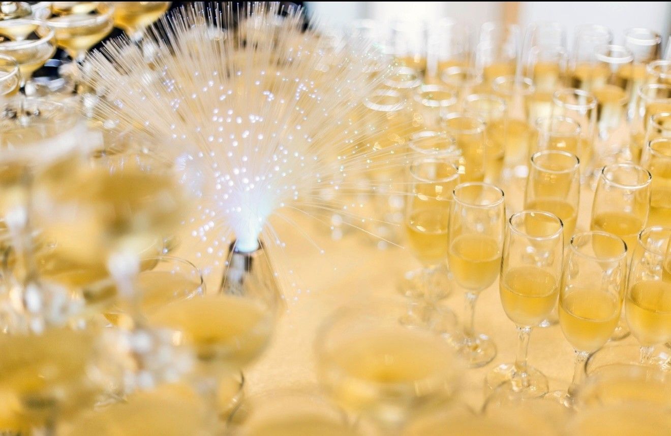 Elegant event hall set for a celebration. Round tables with floral centerpieces, purple and white draping, chandeliers. Elegant event hall set for a celebration. Round tables with floral centerpieces, purple and white draping, chandeliers.