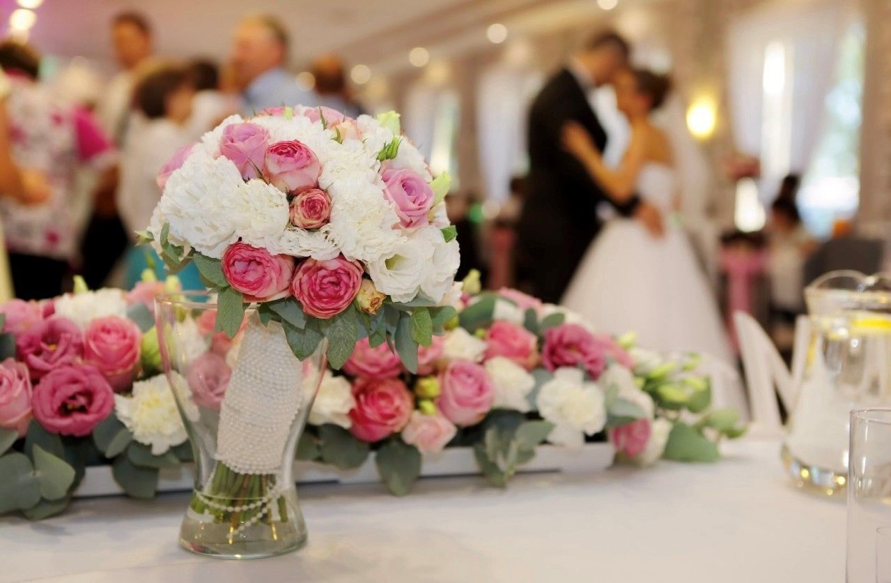 Elegant event space with round tables, floral centerpieces, and place settings.