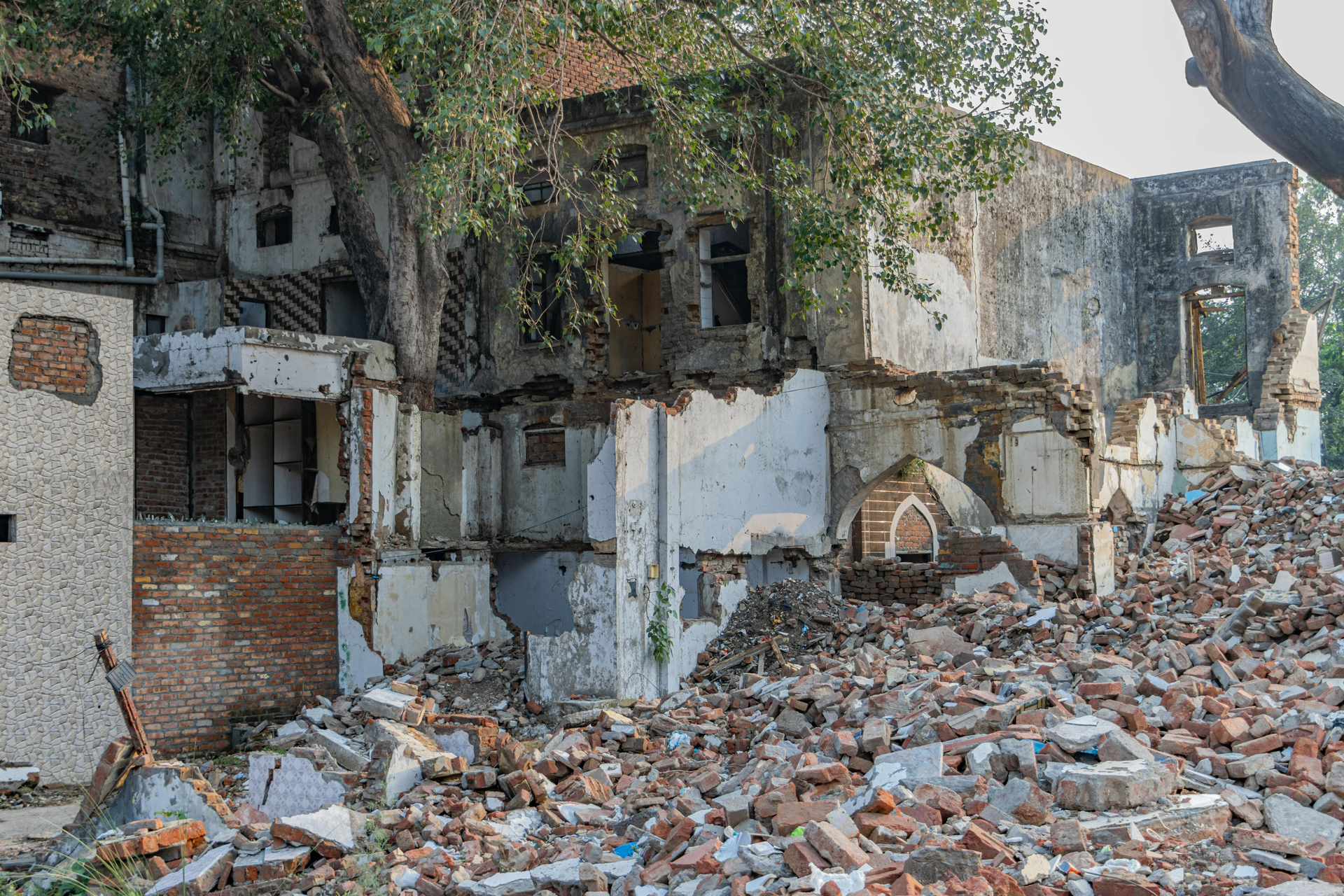 Residential lot demolition in progress, showing damaged building with scattered bricks and concrete