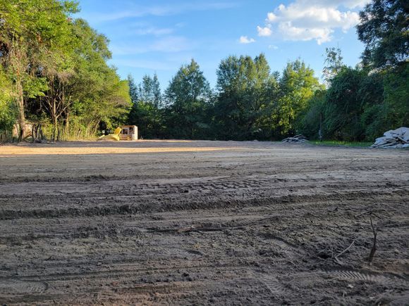 A dirt field with trees in the background and a blue sky in the background.