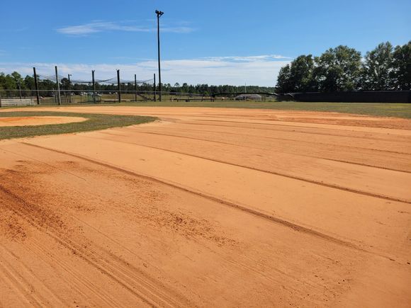 An empty baseball field with a blue sky in the background.