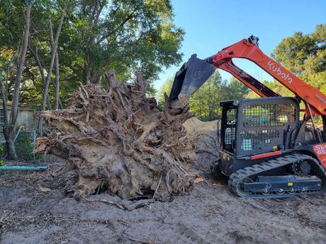 A large tree stump is being removed by a bulldozer.