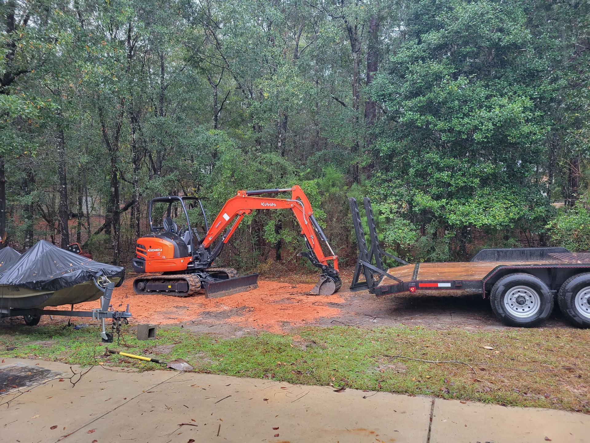 An excavator is digging a hole in the ground next to a trailer.