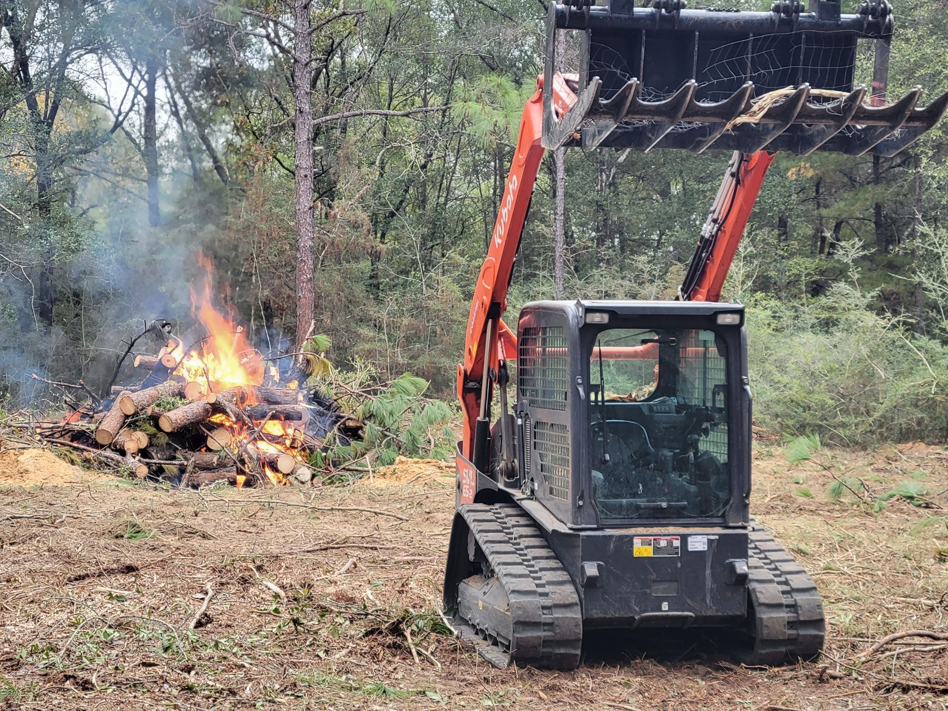 A bulldozer is moving a pile of logs in a field.