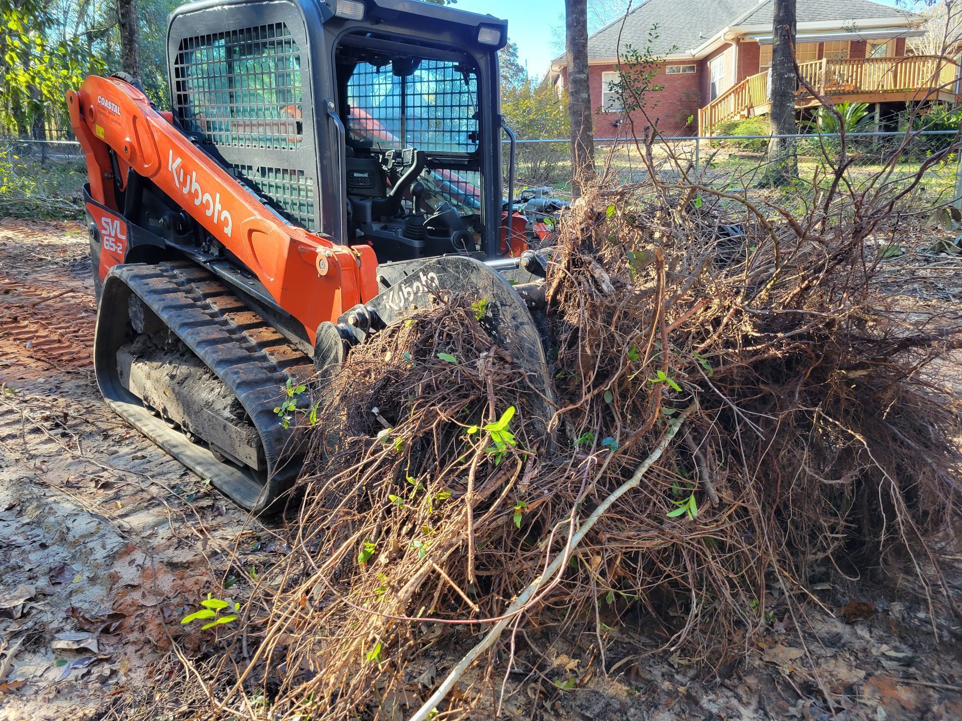 A bulldozer is moving a pile of branches in the dirt.