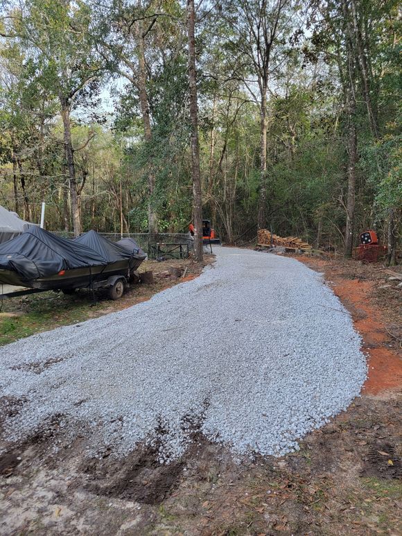 A gravel driveway is being built in the middle of a forest.