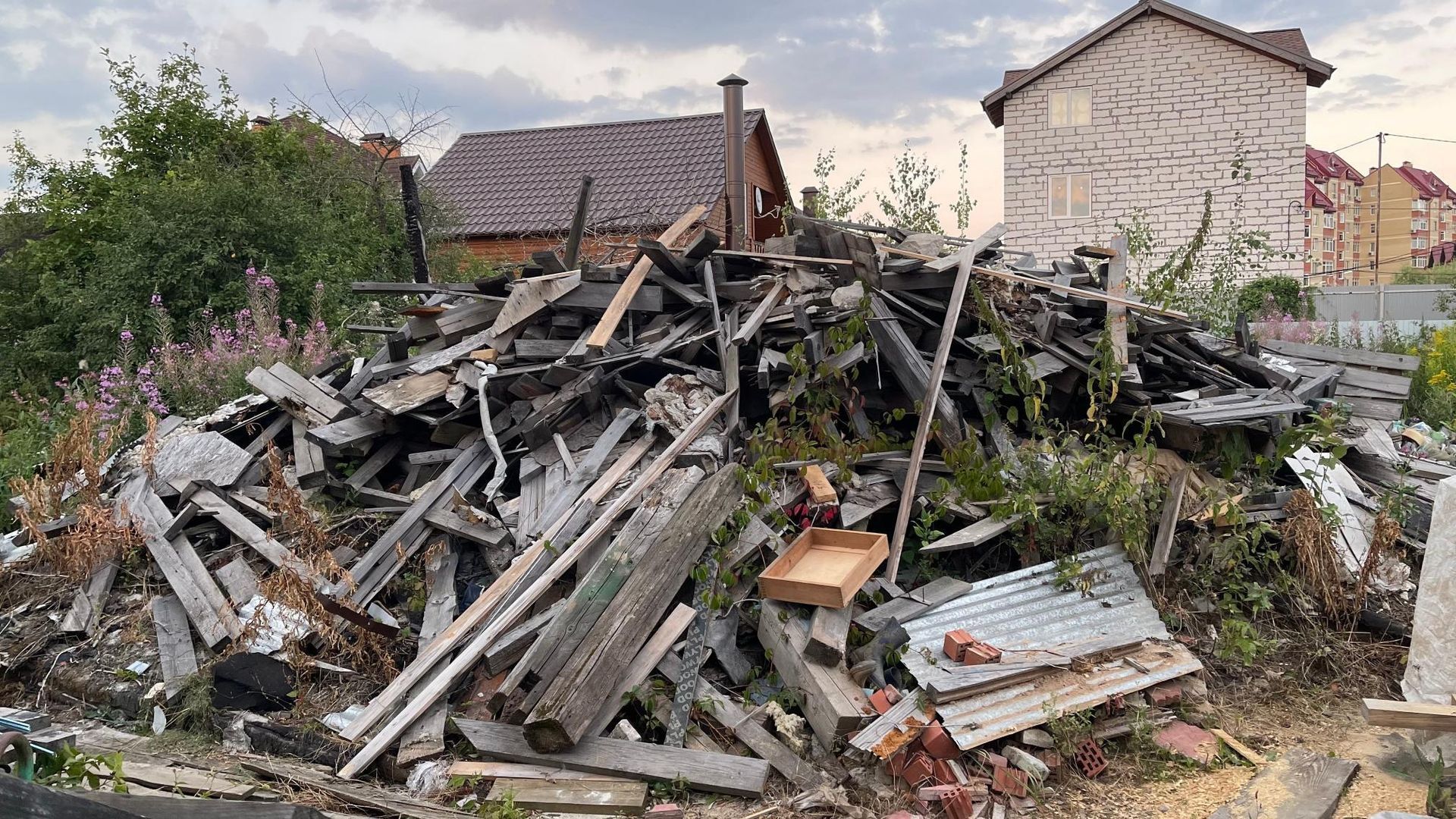 A pile of wood is sitting in front of a house.