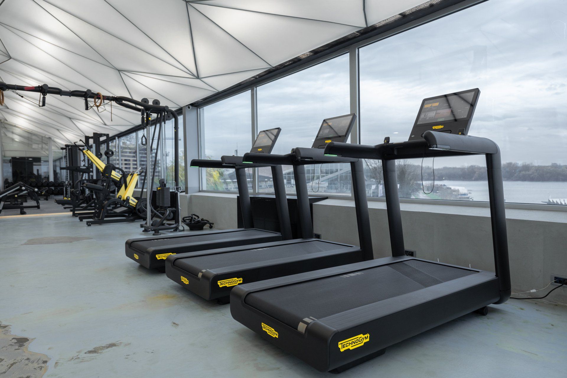 a row of Technogym treadmills are lined up in a gym .