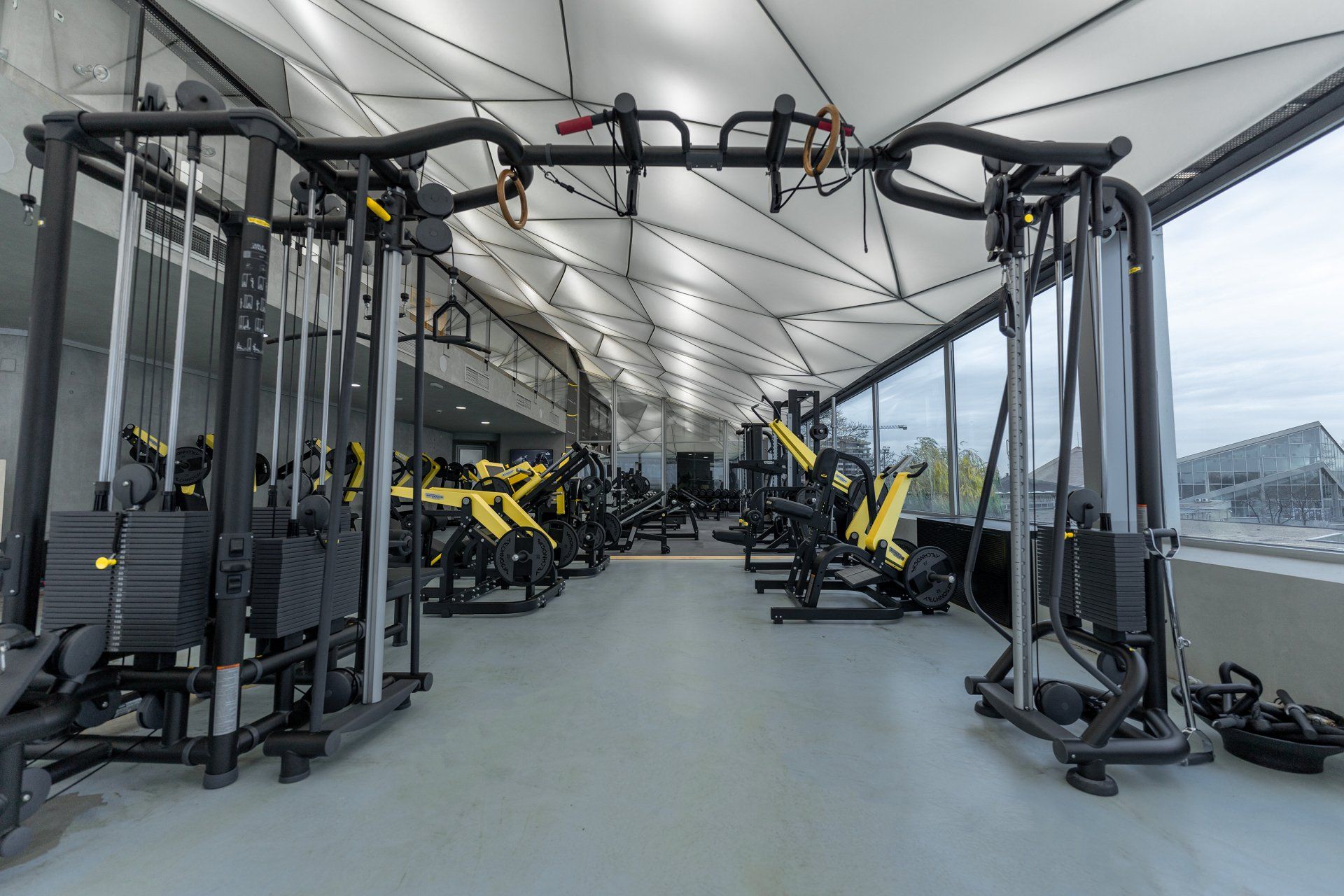 a gym filled with lots of exercise equipment and a lot of windows .