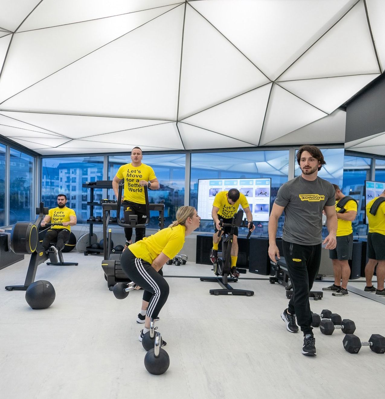 a group of people are working out in a gym wearing yellow shirts