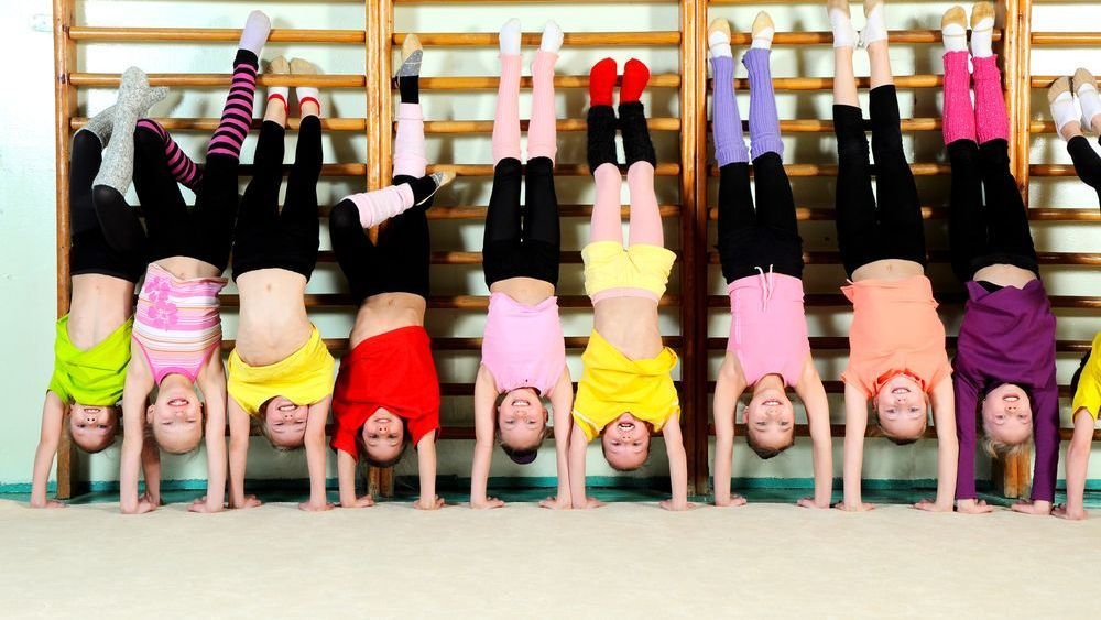 A group of children are doing handstands in a gym.