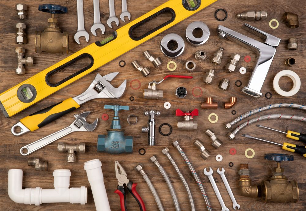 A wooden table topped with a variety of plumbing tools.