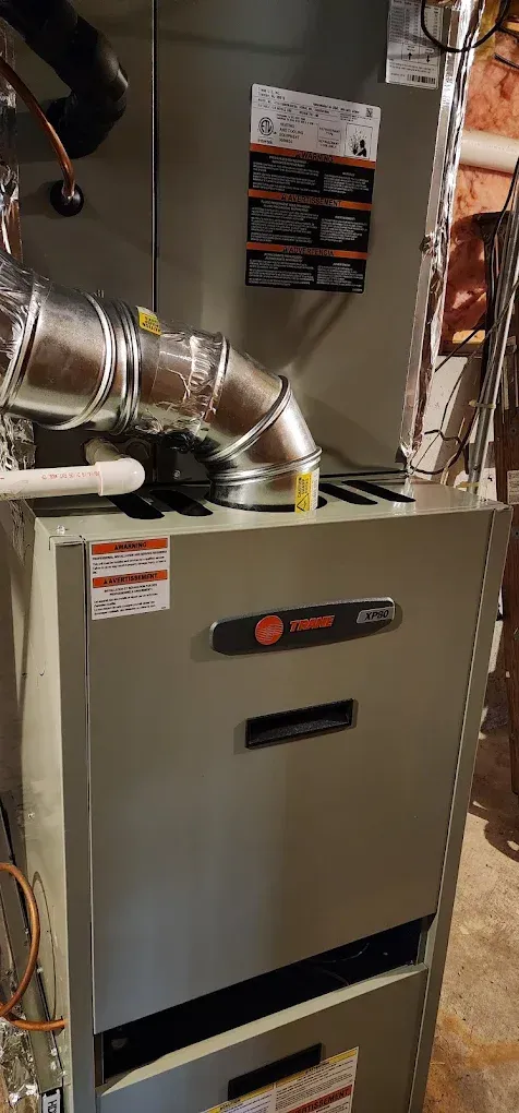 A Trane furnace with ductwork in a basement setting.