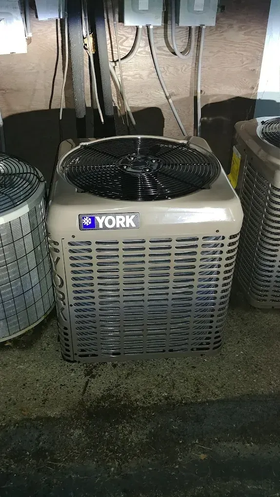 York air conditioning unit, outdoor setting, gray metal casing, black fan, electrical components.