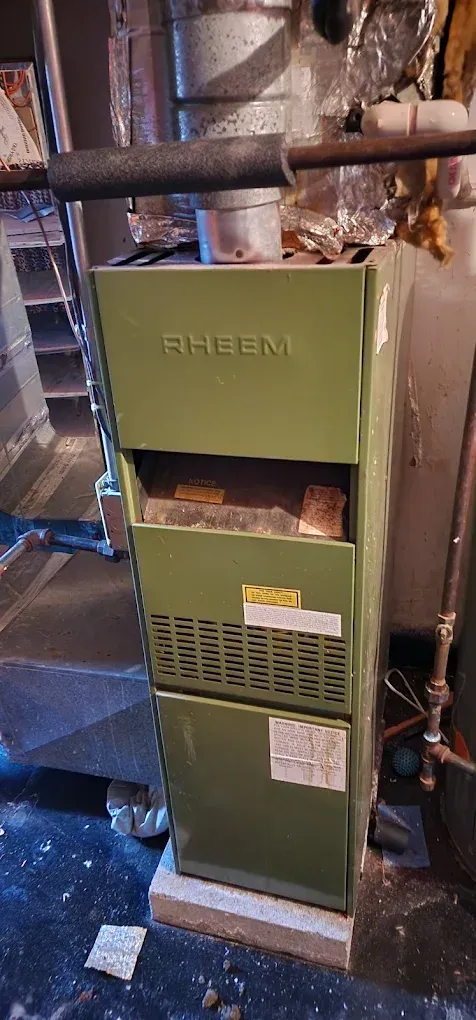 Green Rheem furnace in a basement.