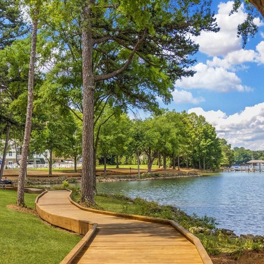 A wooden walkway leading to a lake surrounded by trees.