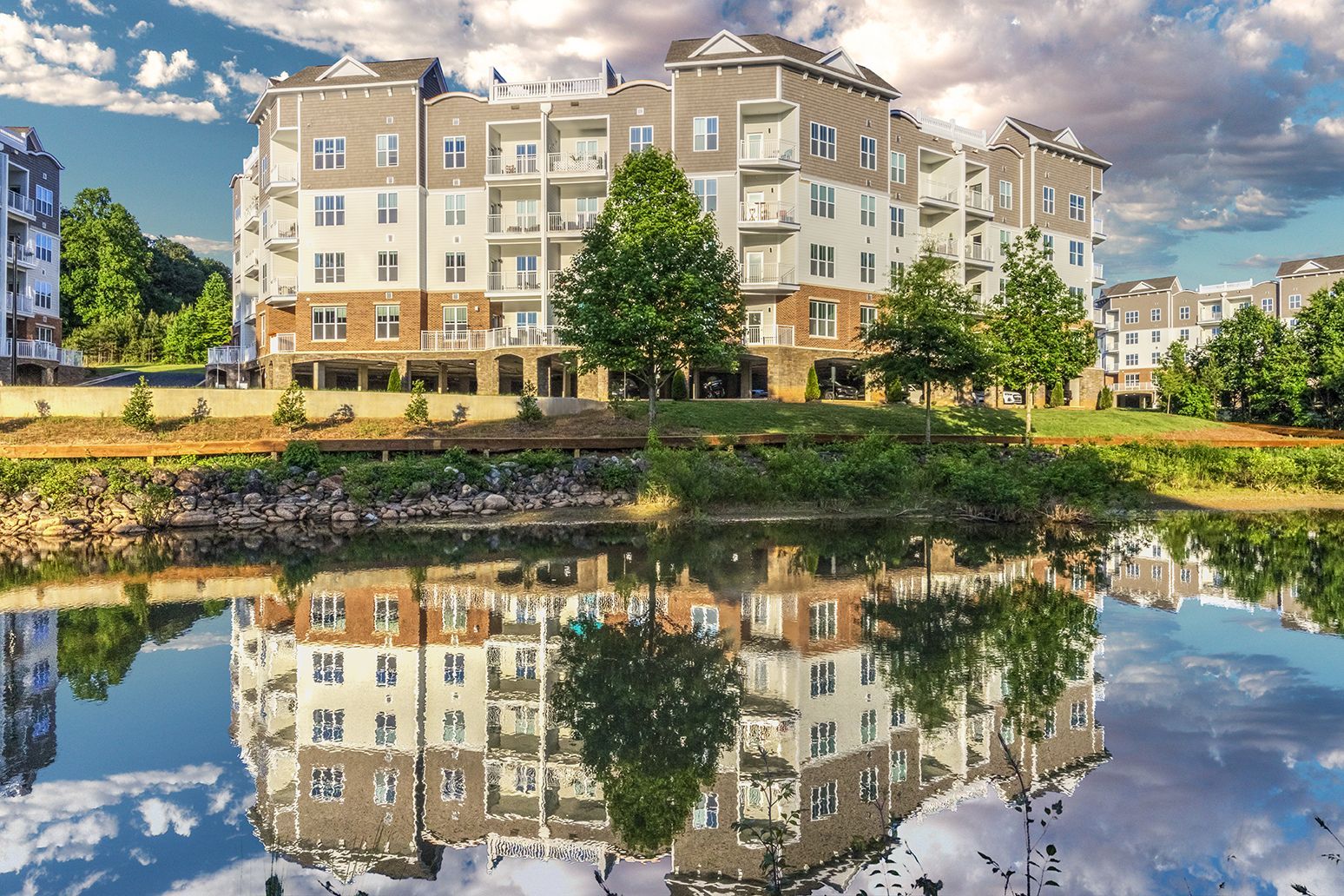 A large apartment building is reflected in a body of water at The Osprey in Mooresville, NC.