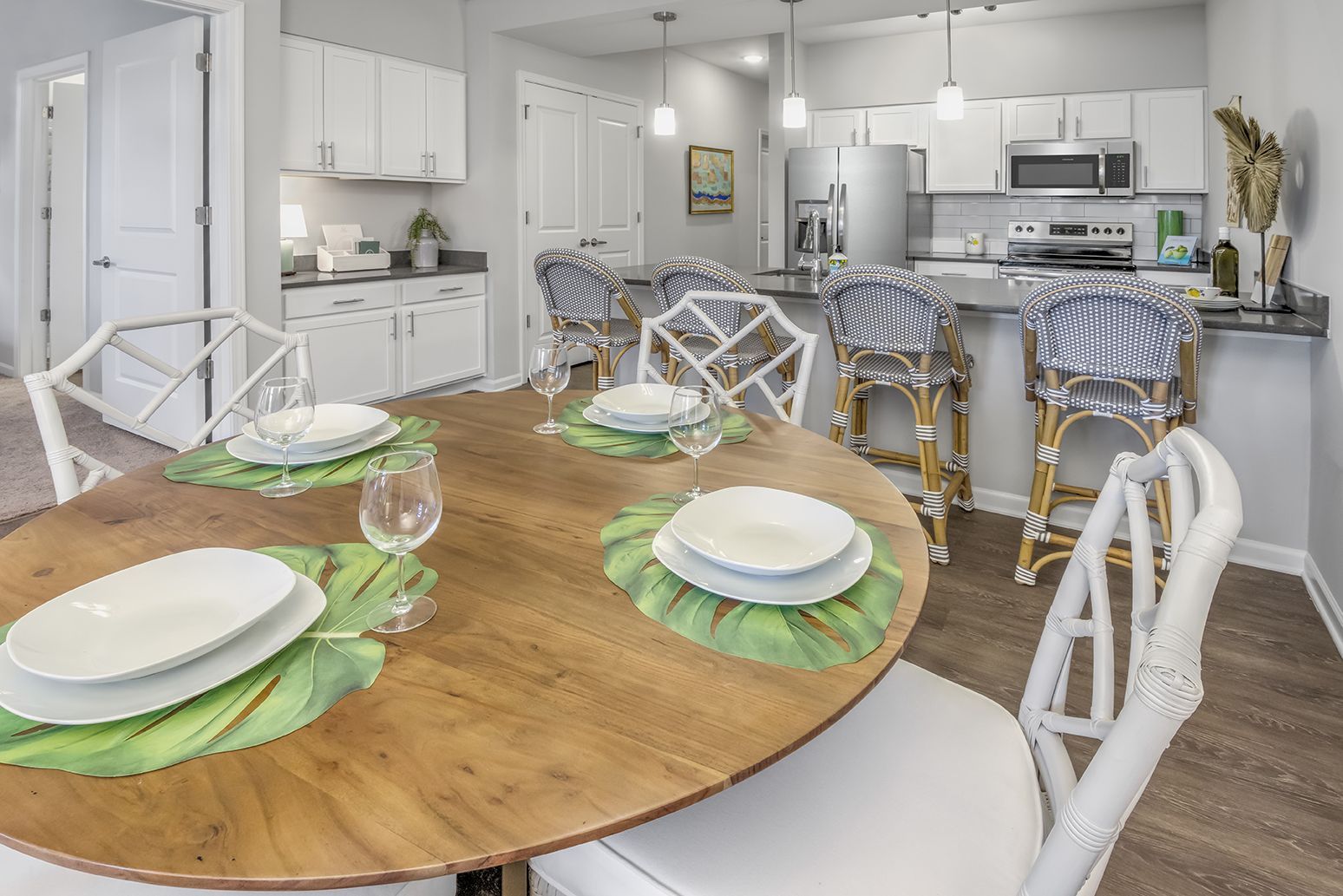 A dining room table with plates and glasses on it in a kitchen at The Osprey in Mooresville, NC.