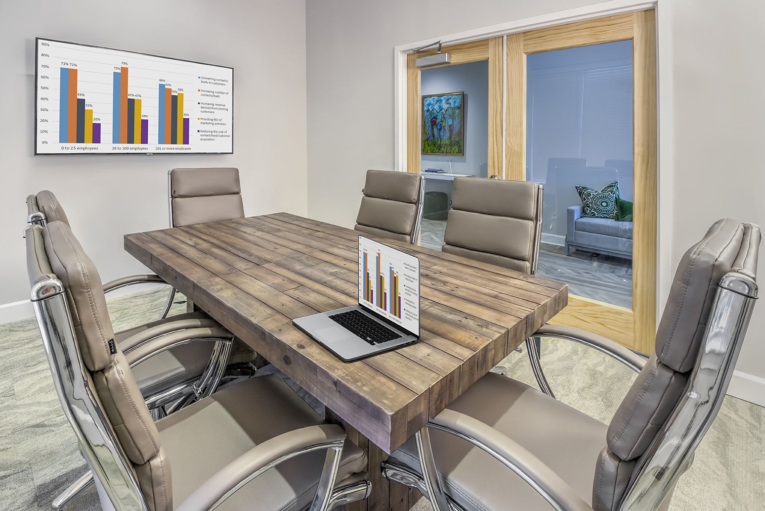 A conference room with a wooden table and chairs and a laptop on the table at The Osprey in Mooresville, NC.
