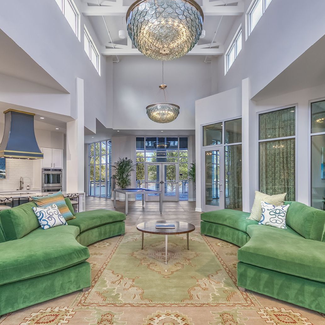 A living room with green furniture and a chandelier hanging from the ceiling.