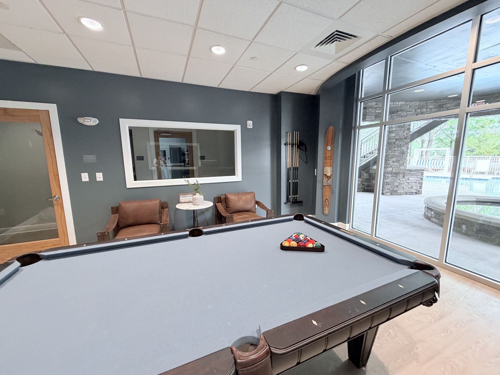 Outdoor pool area with gazebos, lounge chairs, and building with copper roof and brick facade.
