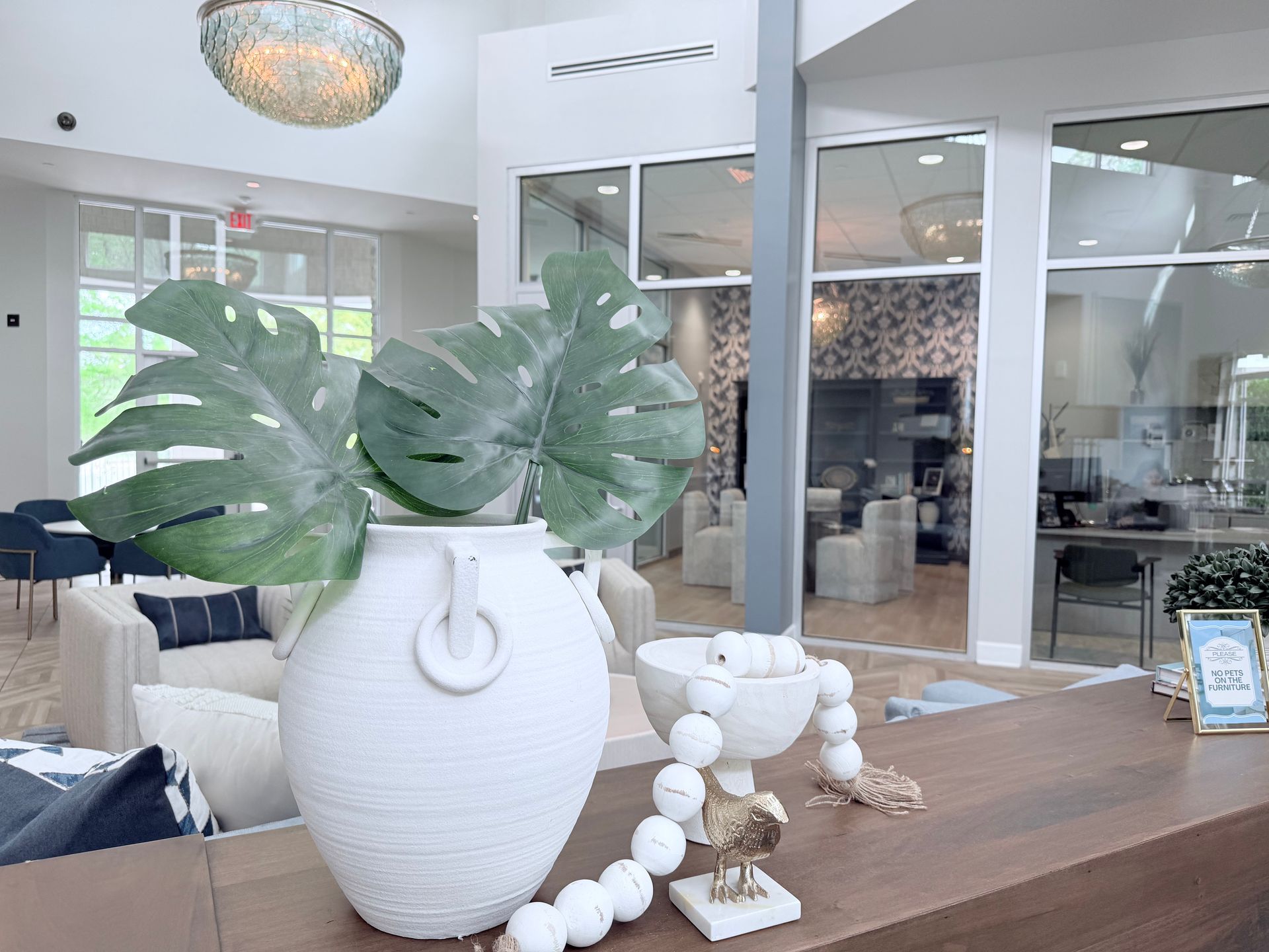Pool area with blue water, white lounge chairs, and a multi-story building under a blue sky with clouds.