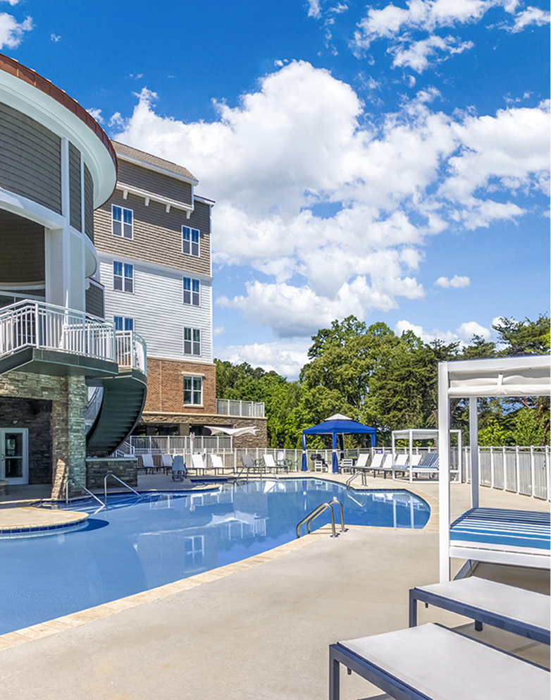 A man and a woman are standing in front of a wall of wine bottles.