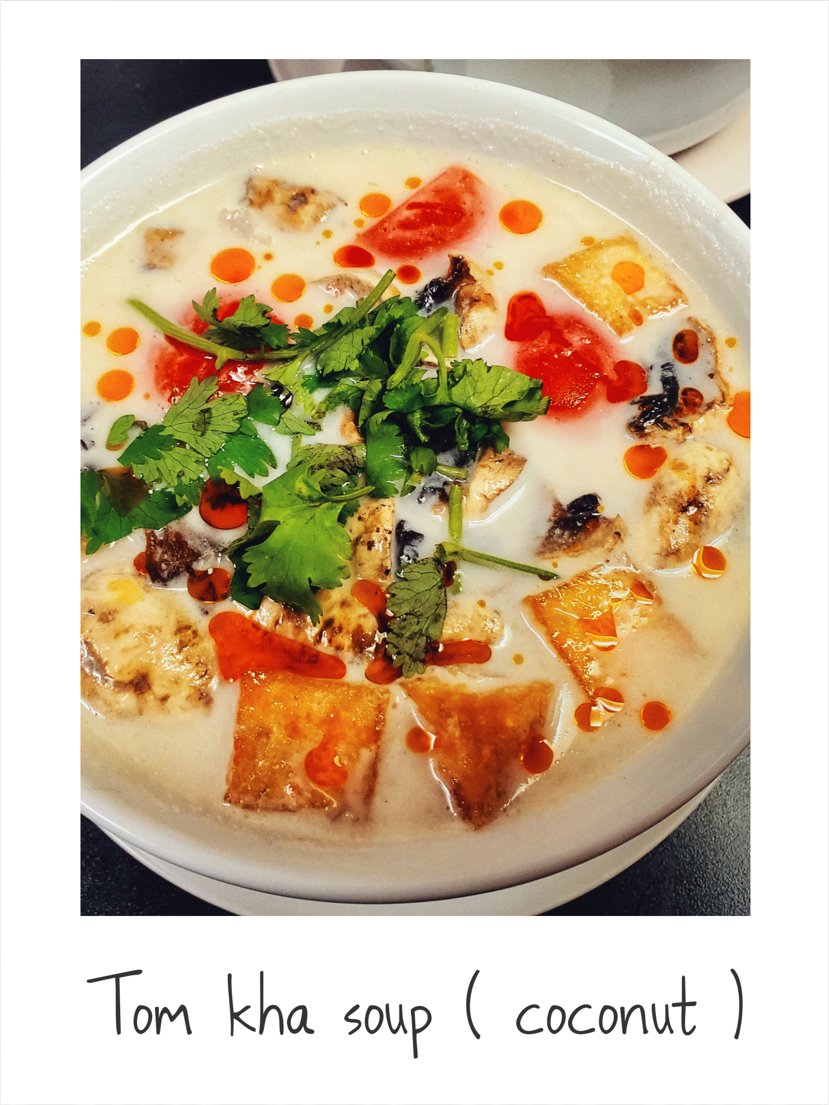 A bowl of tom kha soup with coconut in the corner